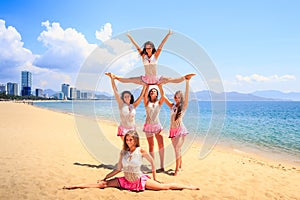 Cheerleaders perform Straddle Stunt with one split on beach photo