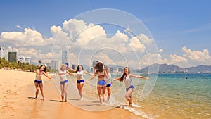 cheerleaders in uniform run gambol about shallow water on beach