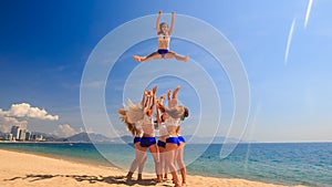 cheerleaders in white blue show Basket Toss on beach