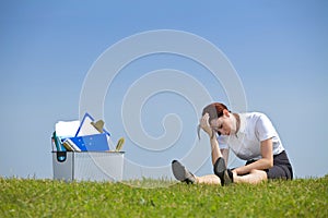 Cheerless businesswoman sitting next to basket full of files in park