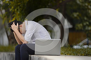 Cheerless pensive Asian business man in formal wear suffering from stress at outside of office.