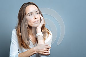 Cheerless thoughtful woman holding her cheek