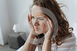 Cheerless young woman holding her temples