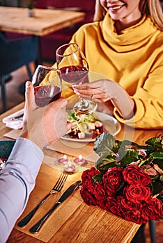 Cheers for happiness. Close-up of couple holding red wine in restaurant