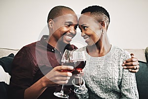 Cheers to many more years of loving you. a happy young couple drinking wine and relaxing together at home.
