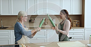 Cheery mature woman her adult daughter having fun in kitchen