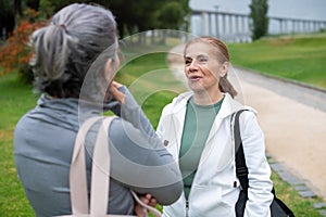 Cheery senior friends talking in park