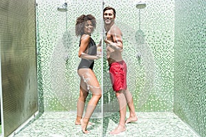 Cheery youthful couple having fun taking shower together