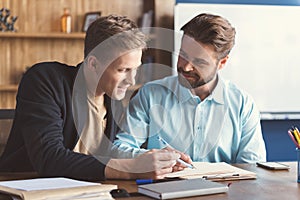 Cheery youthful guys filling job application in office