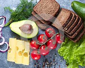 Cheese, avocado, tomato, green sprouts, black bread, salad, onion. Grey background