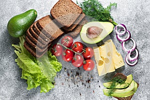 Cheese, avocado, tomato, green sprouts, black bread, salad, onion. Grey background