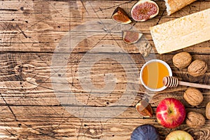 Cheese, baguette honey and nuts snacks on the rustic wooden table top with copy space.