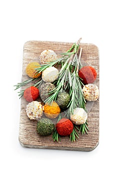 Cheese balls covered with various spices and nuts decorated with rosemary sticks isolated on white