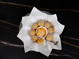 The cheese balls in the dish with black background