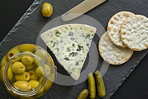 Cheese board with blue mold cheese, olives, pickles and crackers