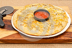 Cheese bread and marinara sauce close up on wooden cutting board