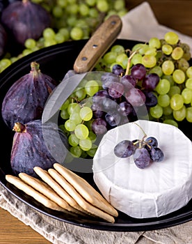 Cheese Brie Camembert with Figs and Grapes on wooden table Food for Wine Figs Green and Red Grapes Crackers Knife Plate Snacks Ver