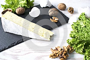 Cheese brie, nuts and verdure on a white wooden table. Top view with copy space.