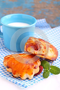 Cheese buns with cherry jam. Blue cup with milk