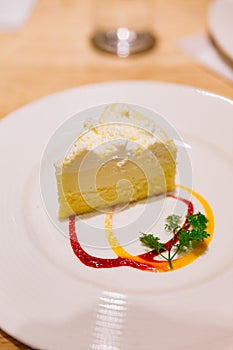 Cheese cake with red and yellow sauces on white plate at cafe in Otaru. Hokkaido, Japan photo