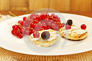 Cheese cakes with berries of red currant black raspberry and sour cream
