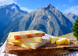 Cheese collection, French comte, beaufort or abondance cow milk cheese served outdoor with Alps mountains peaks on background