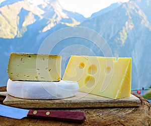 Cheese collection, French emmental, tomme and reblochon de savoie cheeses served outdoor in Savoy region, with Alpine mountains