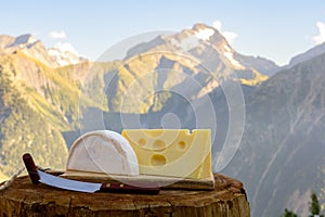 Cheese collection, French reblochon and emmental de savoie cheese served outdoor in Savoy region, with Alpine mountains peaks on