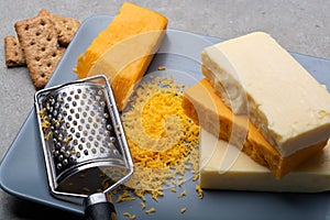 Cheese collection, matured and orange original British cheddar cheese in blocks and grated served on grey plate