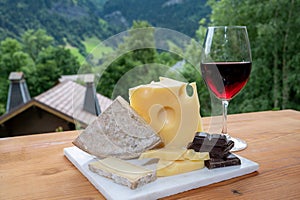 Cheese collection, Swiss cow cheese emmental, tomme and dark chocolate, glass of red wine from Savoie and mountains village in