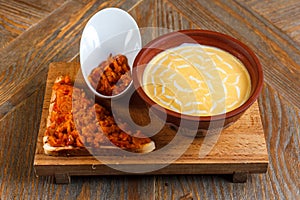 Cheese cream soup stands on a wooden tray with a piece of bread