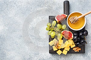 Cheese cubes, fresh fruit figs grapes Honey walnut on wooden chopping Board. Copy space