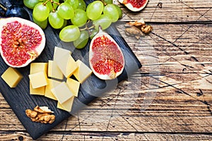 Cheese cubes, fresh fruit figs grapes Honey walnut on wooden chopping Board. Copy space.