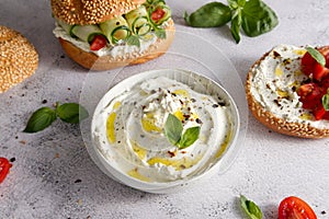 Cheese curd spread for breakfast with herbs, sun-dried tomatoes and olive oil close-up