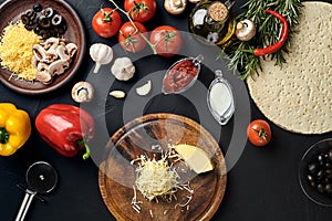 Cheese, different vegetables on black table. Ingredients for traditional italian pizza.