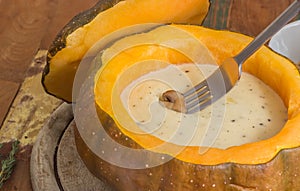 Cheese fondue in a roasted pumpkin with chestnut mushroom on a f