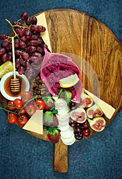 Cheese and fruit charcuterie dessert grazing platter on wooden board.