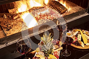 Cheese and fruit plate on the table by the fireplace. A sumptuous feast of fresh fruits and veggies, rustic breads, cheese and