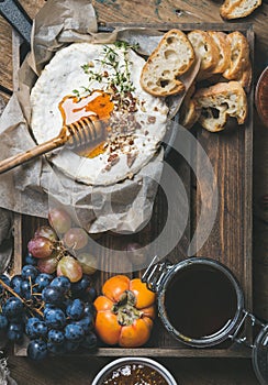 Cheese, fruit and wine set over wooden background, copy space