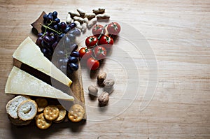 Cheese with grapes and cherry tomatoes, cracker, nuts, fruits and nuts. View from above. Cheese on a visible background. Copy
