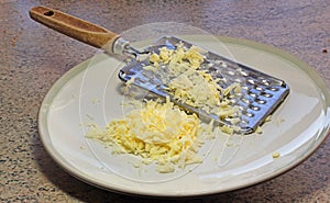 Cheese grater and cheese on a dish.