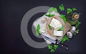 Cheese, greens and spices on a dark background. Food background.