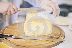 Cheese heads on market counter, seller sells cheese, cut cheese heads on wooden market board. Selective focus