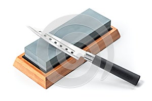 Cheese knife laying on a whetstone isolated on white background