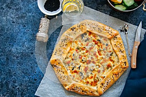 Cheese and labneh savory galette with olives on a baking paper.