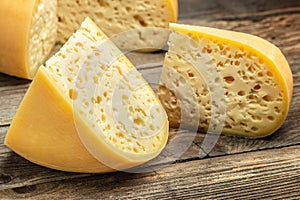 Cheese maasdam with big holes on a wooden background. Large selection of cheeses on typical farmer market. Ecology and eco-