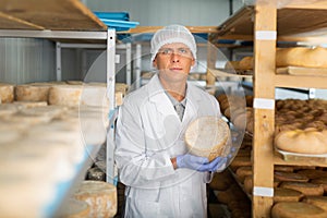 Cheese maker controlling maturing process of cheese wheels