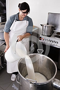 Cheese Maker pours milk into a steel container