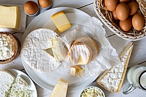 Cheese, milk, dairy products and eggs on rustic white wood from