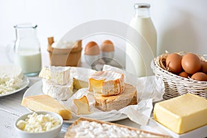 Cheese, milk, dairy products and eggs on rustic white wood background.